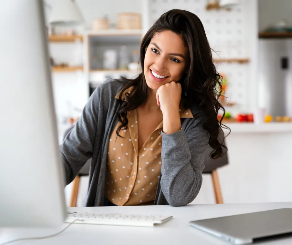 a woman sitting at a desk looking at a computer screen