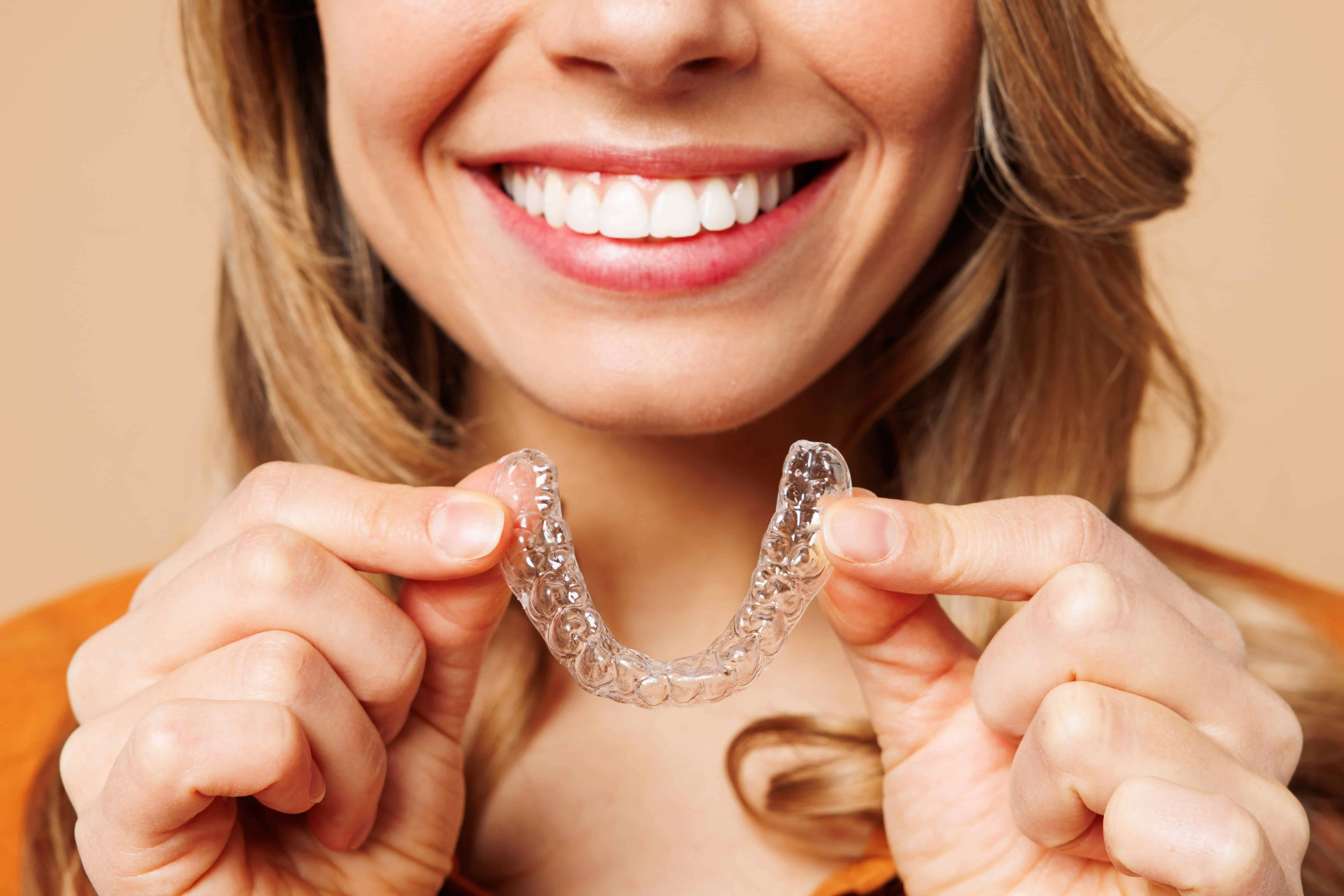 a woman holding a clear plastic retainer